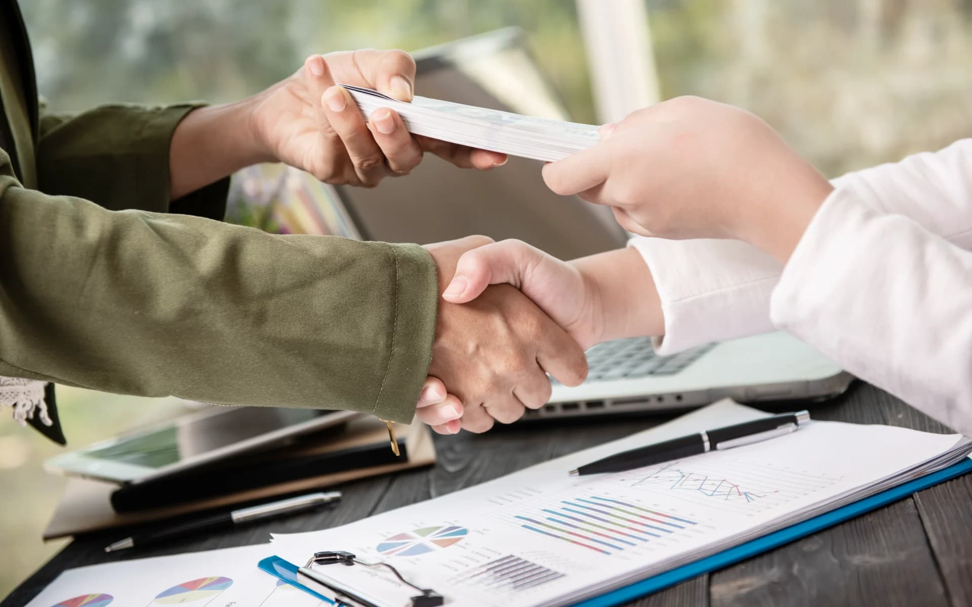 Two people shaking hands as a deal closes and the payment is handed over