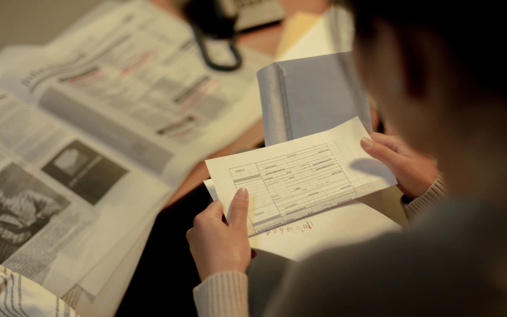 Someone reading a payment statement at a desk, holding the page up to check the figures on it